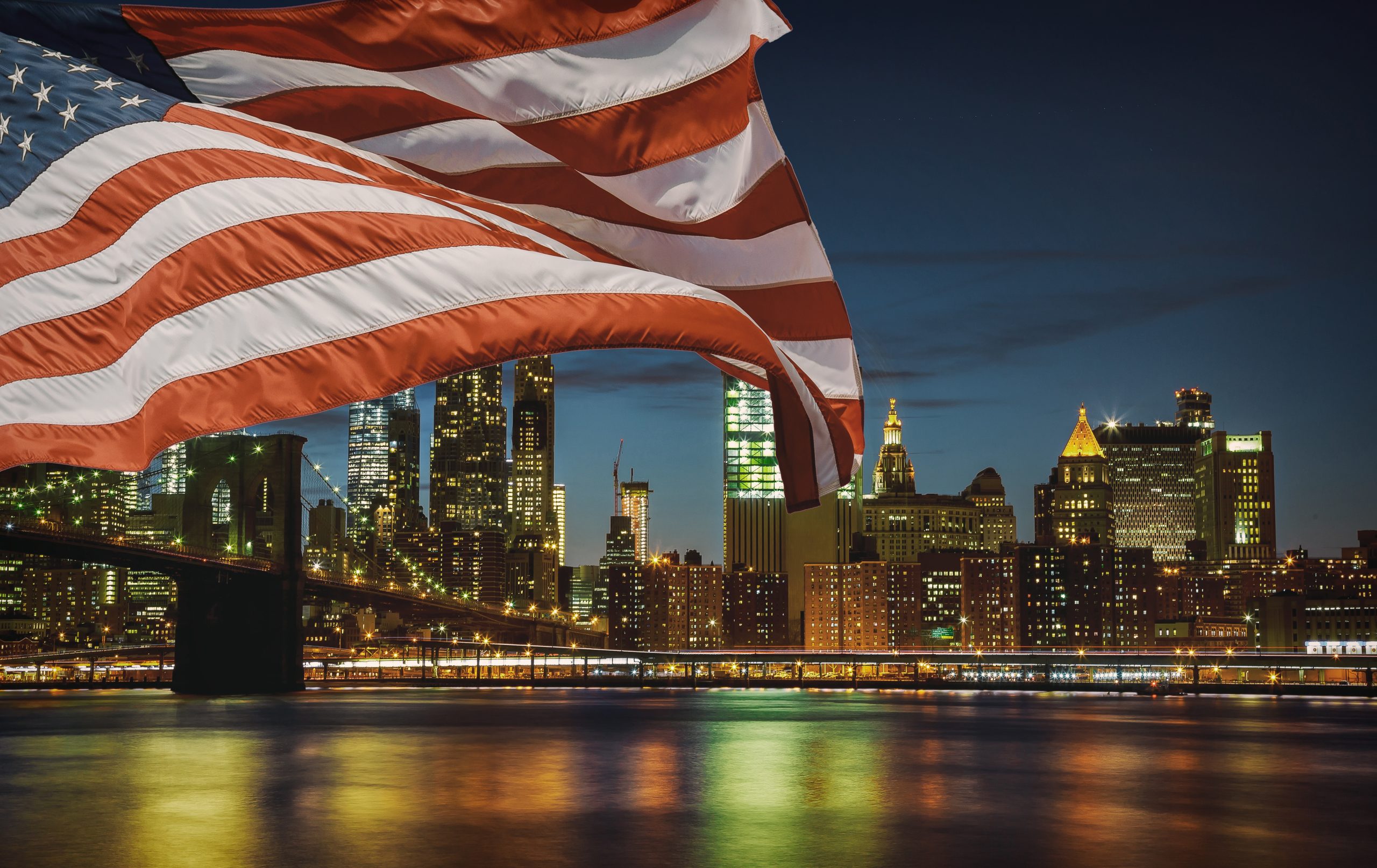 United States flag New York City's Brooklyn Bridge and Manhattan skyline illuminated